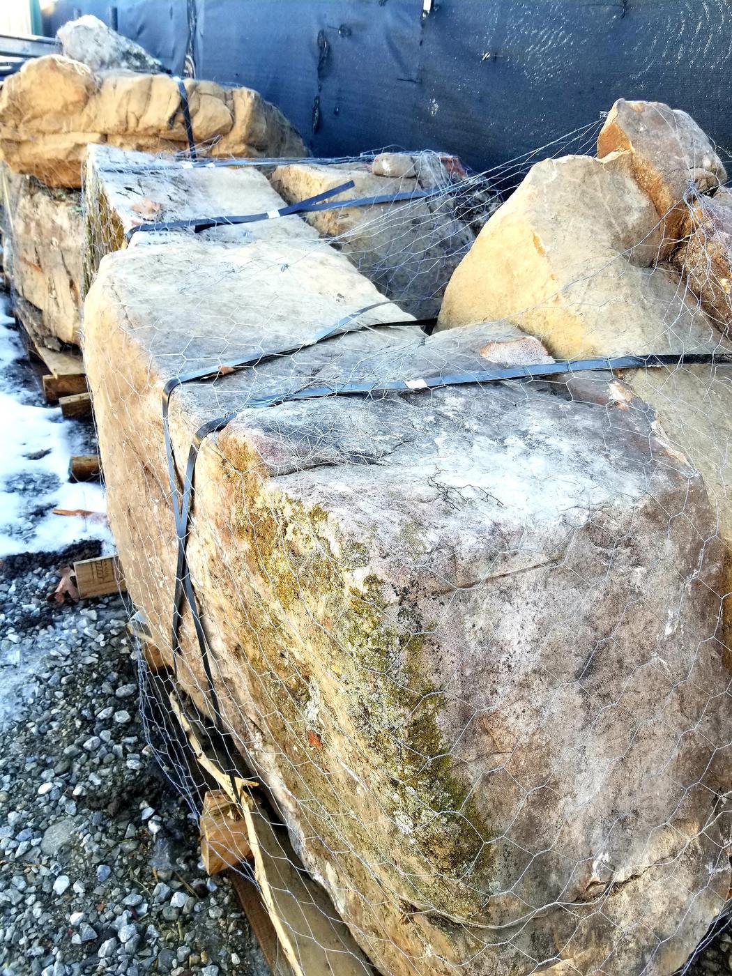 Large sandstone boulders strapped to pallets in the yard
