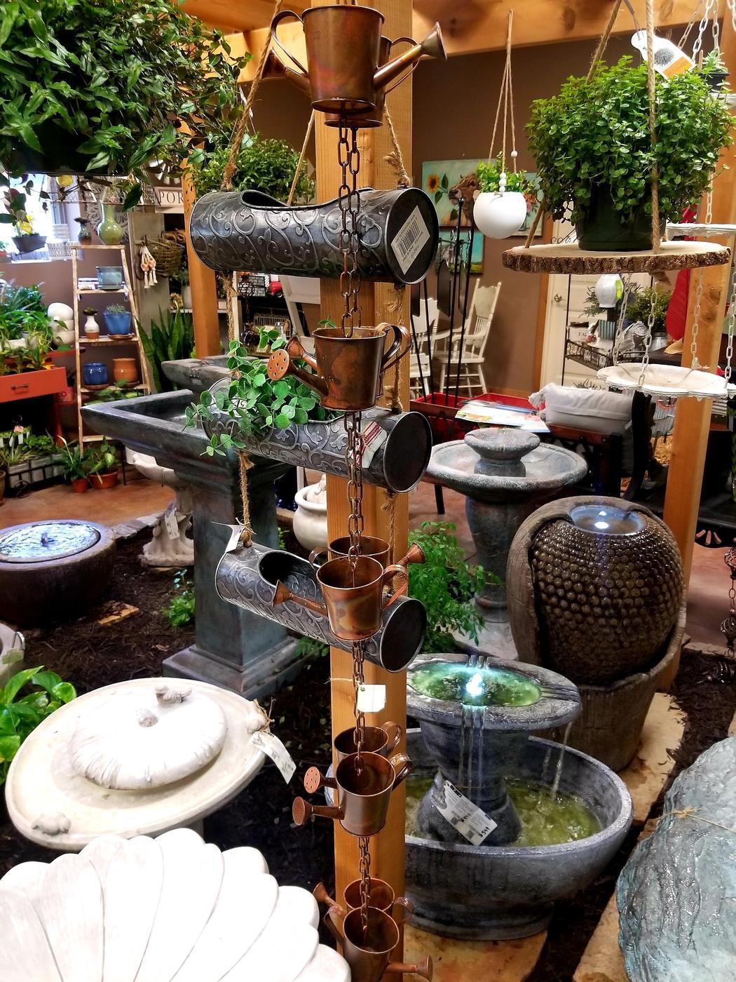 Inside the greenhouse: hanging baskets, a watering can rain chain, birdbaths and running fountains