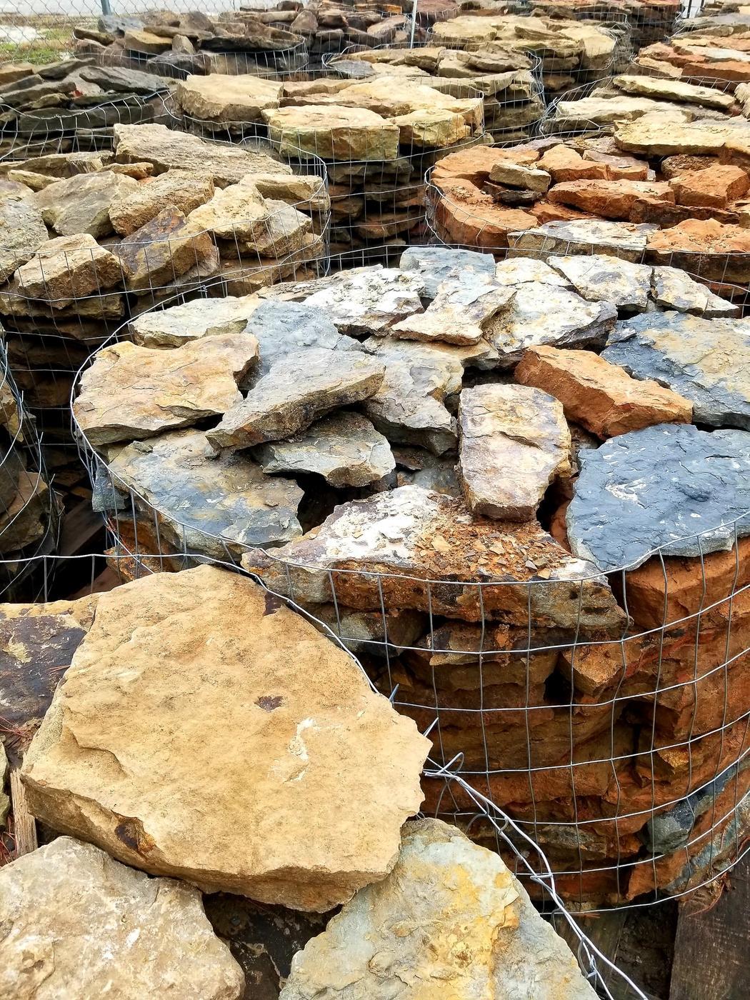 Pallets of flagstone in gold, blue grey and rust at the stone yard